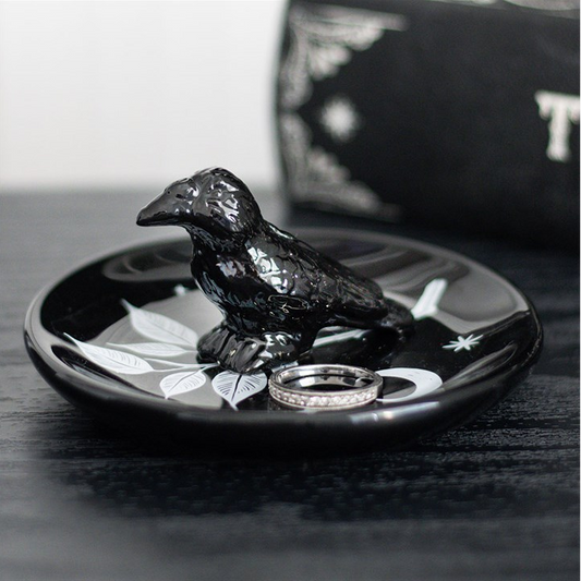 Black bird-shaped ring holder with rings on a dark surface