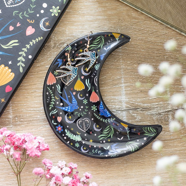 Decorative moon-shaped plate with colorful designs on a wooden surface.