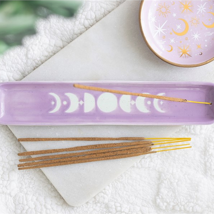 A lavender rectangular incense holder with a moon phase design, shown with incense sticks on a white marble tray and a matching decorative bowl in the background.